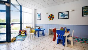 Ein Kinderspielzimmer mit Tischen, Stühlen und Lernspielzeug.