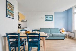 Uma sala de estar moderna com sofá, mesa de jantar, cadeiras e área de cozinha.
