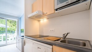A modern kitchen with a dishwasher, a sink, and a built-in oven. - Scenic 6-Person Duplex Retreat (Île-aux-Moines)
