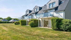 A row of modern residential buildings with balconies, a well-maintained lawn, and a clear sky. - Scenic 6-Person Duplex Retreat (Île-aux-Moines)