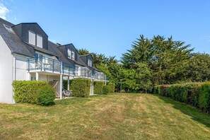 Une maison moderne dotée d’un espace extérieur couvert, d’une pelouse bien entretenue et d’une végétation luxuriante.