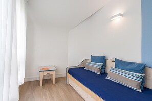 Une chambre à coucher avec un lit, un petit tabouret en bois et une lampe fixée au mur.