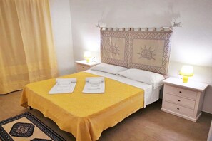 A hotel room with a bed, two bedside tables, a nightstand, a lamp, a curtain, and a patterned rug. - Premium Sea View Family Retreat (Badesi)