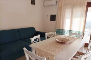 Ein Essbereich mit Tisch, Stühlen, einem blauen Sofa und einer Tischläufer mit Muster.