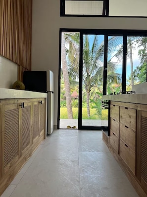Una cocina moderna con armarios de madera, un ventanal con vistas a palmeras y follaje.