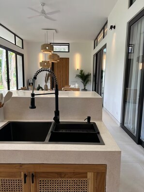 Una cocina moderna con un lavamanos doble, un ventilador de techo y un amplio ventanal.