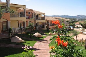 A hotel courtyard with outdoor seating, a paved walkway, and a view of the surrounding landscape. - Spacious Beach Apartment for 6 (Badesi)