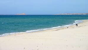 Ein Strand mit freiem Blick auf das Meer, einem Sandufer und einer entfernten Insel.