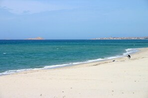 A beach with a clear view of the sea, a sandy shore, and a distant island. - Spacious Beach Apartment for 6 (Badesi)