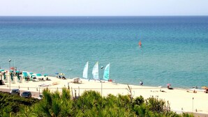 Una playa con vista despejada al mar, varias sombrillas y algunas personas.