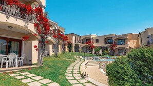 Un patio de hotel con piscina, mobiliario exterior y césped cuidado.
