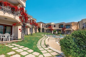 A hotel courtyard with a swimming pool, outdoor seating, and a well-maintained lawn. - Chic Sardinian Escape by the Beach (Badesi)