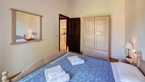 Un dormitorio con cama, armario, espejo y puerta que da al baño.