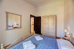 A bedroom with a bed, a wardrobe, a mirror, and a door leading to a bathroom. - Chic Sardinian Escape by the Beach (Badesi)