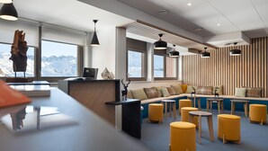 Decoração moderna com balcão de recepção, área de estar e grandes janelas com vista para as montanhas.