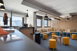 Ein modernes Interieur mit einer Rezeption, einer Sitzecke und großen Fenstern mit Blick auf die Berge.