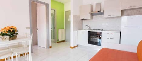 A compact hotel room with a kitchenette, a dining area, and a bed.