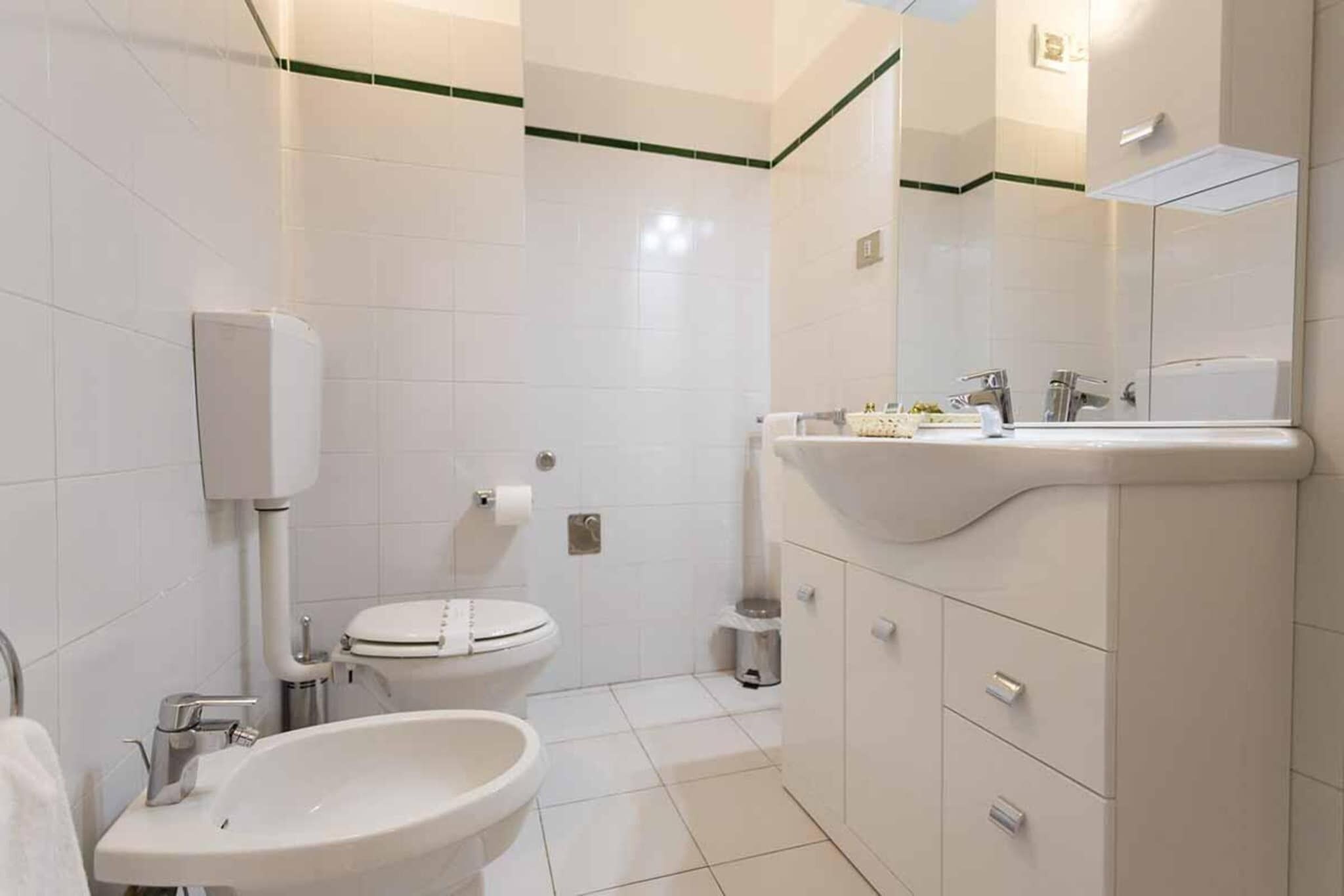 Een badkamer met toilet, wastafel en spiegel.