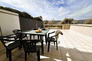 Una terrazza all'aperto con tavolo e sedie, un bicchiere di succo d'arancia e vista sulla campagna.