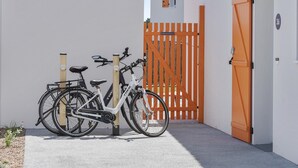 Ein weißes Gebäude mit einem orangefarbenen, geschlossenen Tor, einem weißen Fahrrad und der Zahl '36' an der Wand.