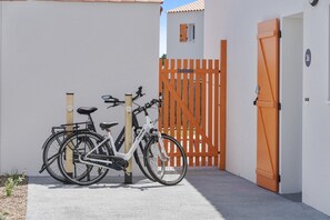 Ein weißes Gebäude mit einem orangefarbenen, geschlossenen Tor, einem weißen Fahrrad und der Zahl '36' an der Wand.