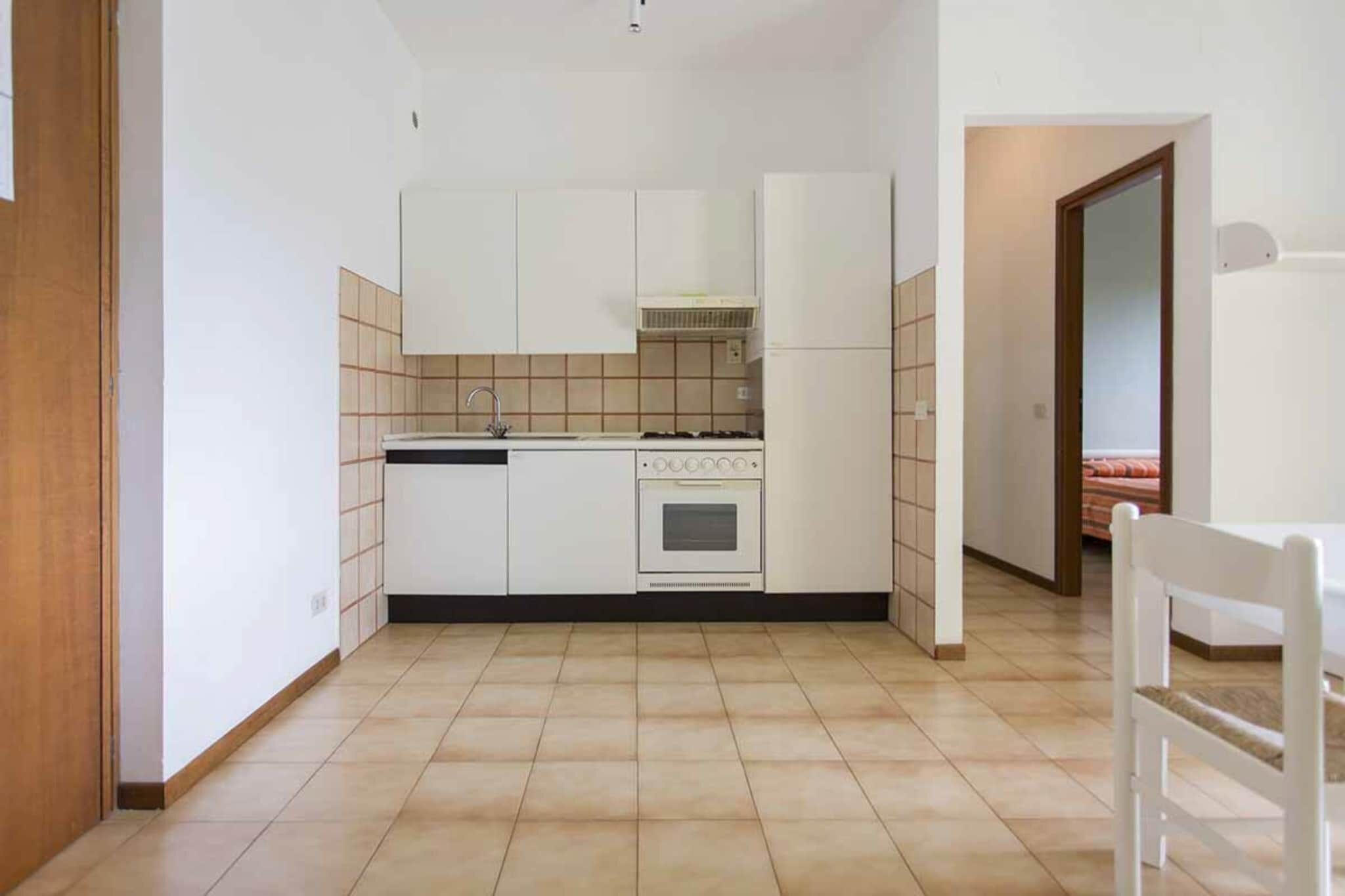 Una cucina compatta con mobili bianchi, un fornello e un lavandino.