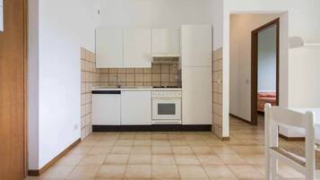 Una cucina compatta con mobili bianchi, un fornello e un lavandino.