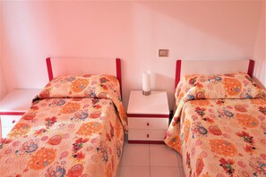 A twin room with two beds, each with a floral-patterned bedspread, a bedside table with a white lamp, and a red headboard. - Stunning Family Retreat near Cinque Terre for 6 (Luni)