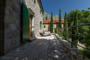 A stone building with a balcony, a stone pathway, and a view of trees and a mountain. - Amazing Villas in Omiš for 8 (Omis)