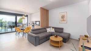 A modern living room with a sectional sofa, dining table, chairs, and a TV. - 6-Person Home with 3 En-Suites (Novigrad)
