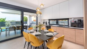 Een moderne keuken met een eethoek, grote ramen en uitzicht op de omgeving.