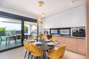 Eine moderne Küche mit Essbereich, großen Fenstern und Blick ins Freie.