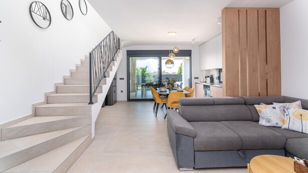 A modern living room with a staircase, a dining area, and a kitchen. - 6-Person Home with 3 En-Suites (Novigrad)