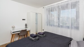 A bedroom with a bed, a desk, a chair, and a window with sheer curtains. - 6-Person Home with 3 En-Suites (Novigrad)