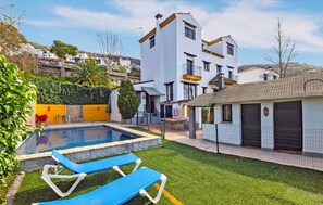 Ein modernes Haus mit Swimmingpool, kleinem Garten und einem separaten Gebäude mit Kachelfassade.