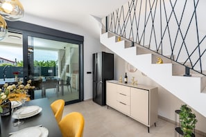 A modern kitchen with a dining area, a staircase with a geometric railing, and a view through a glass door. - Detached Holiday Villa for 6 (Novigrad)