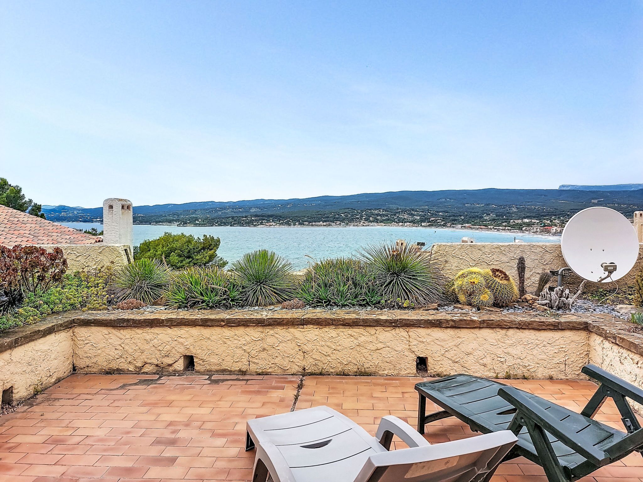 Une terrasse avec vue sur la mer, une antenne parabolique et un mur en pierre.
