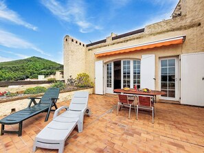 A patio with two sun loungers, a table with chairs, and a view of a hill. - Hameau la Madrague by Interhome (Saint Cyr sur Mer La Madrague)