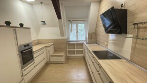 A modern kitchen with built-in appliances, a large window, and a flat-screen TV mounted on the wall. - Landsitz Kammerburg - Verwalterwohnhaus (Lorch)