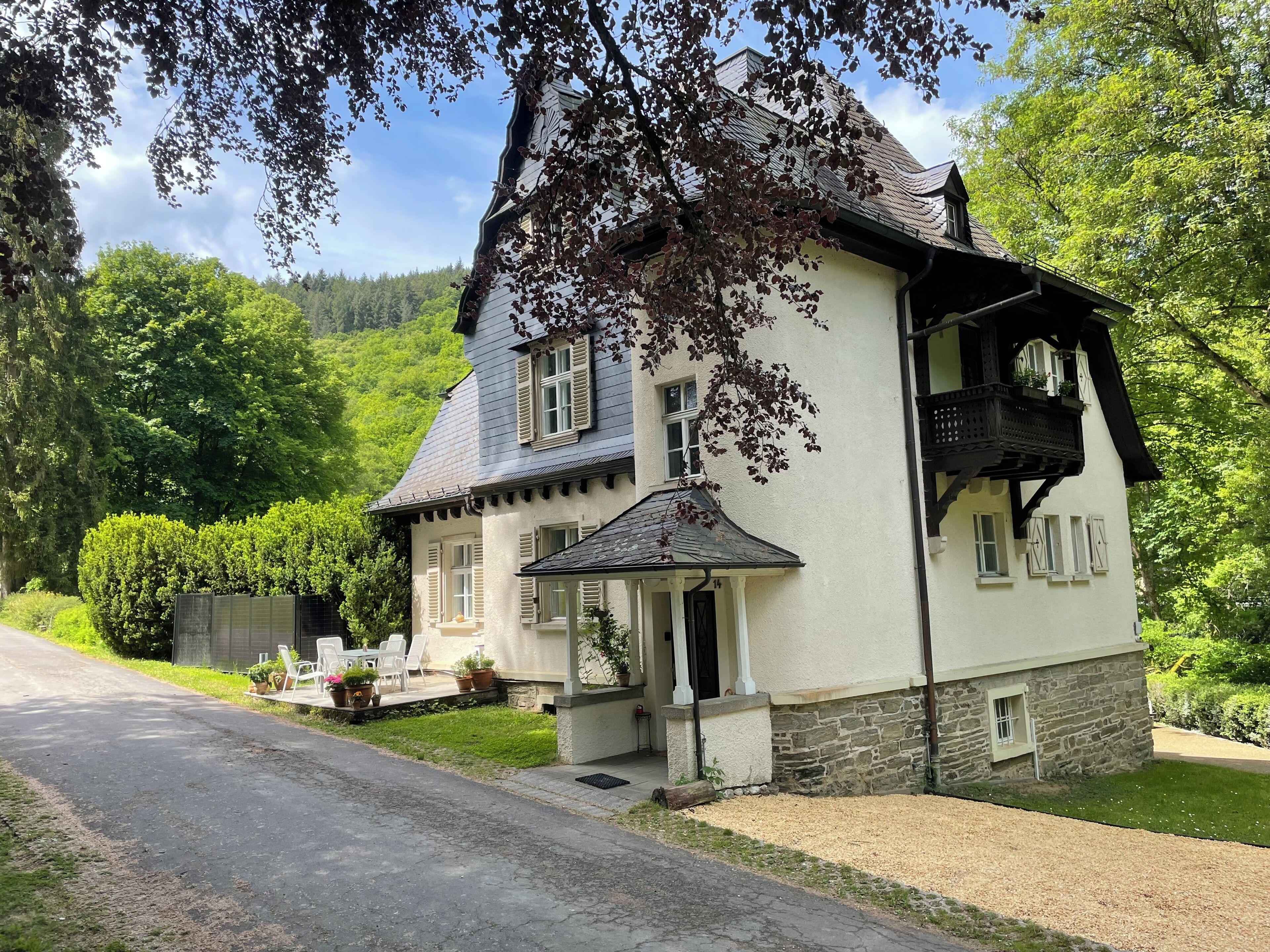 A two-story house with a porch, a stone foundation, and a garden.