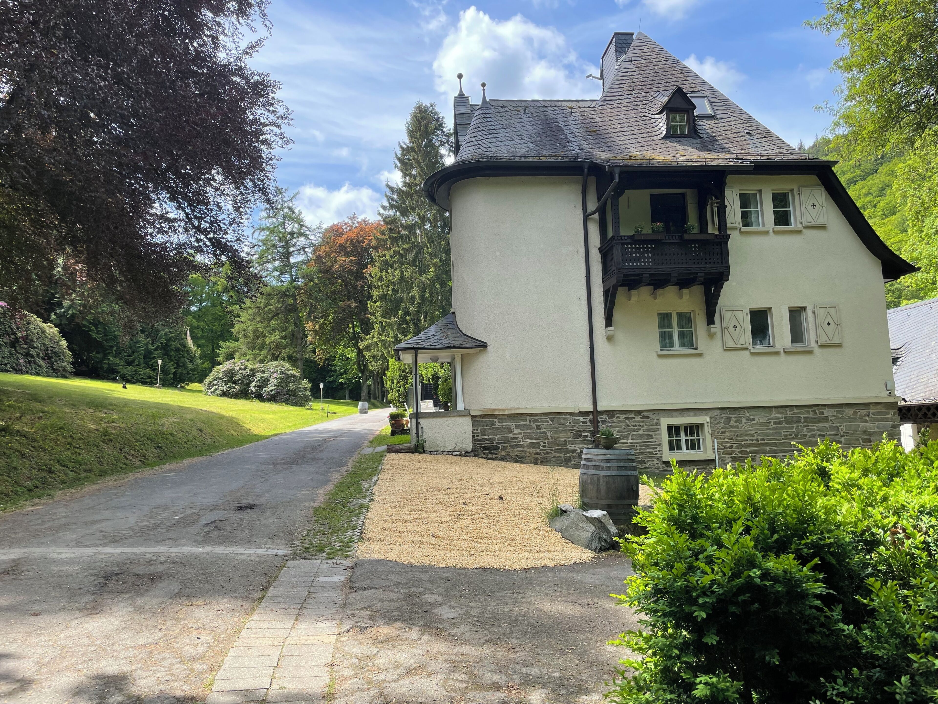 Ein zweistöckiges Haus mit Steinuntergrund, geneigtem Dach und einem kleinen Balkon.
