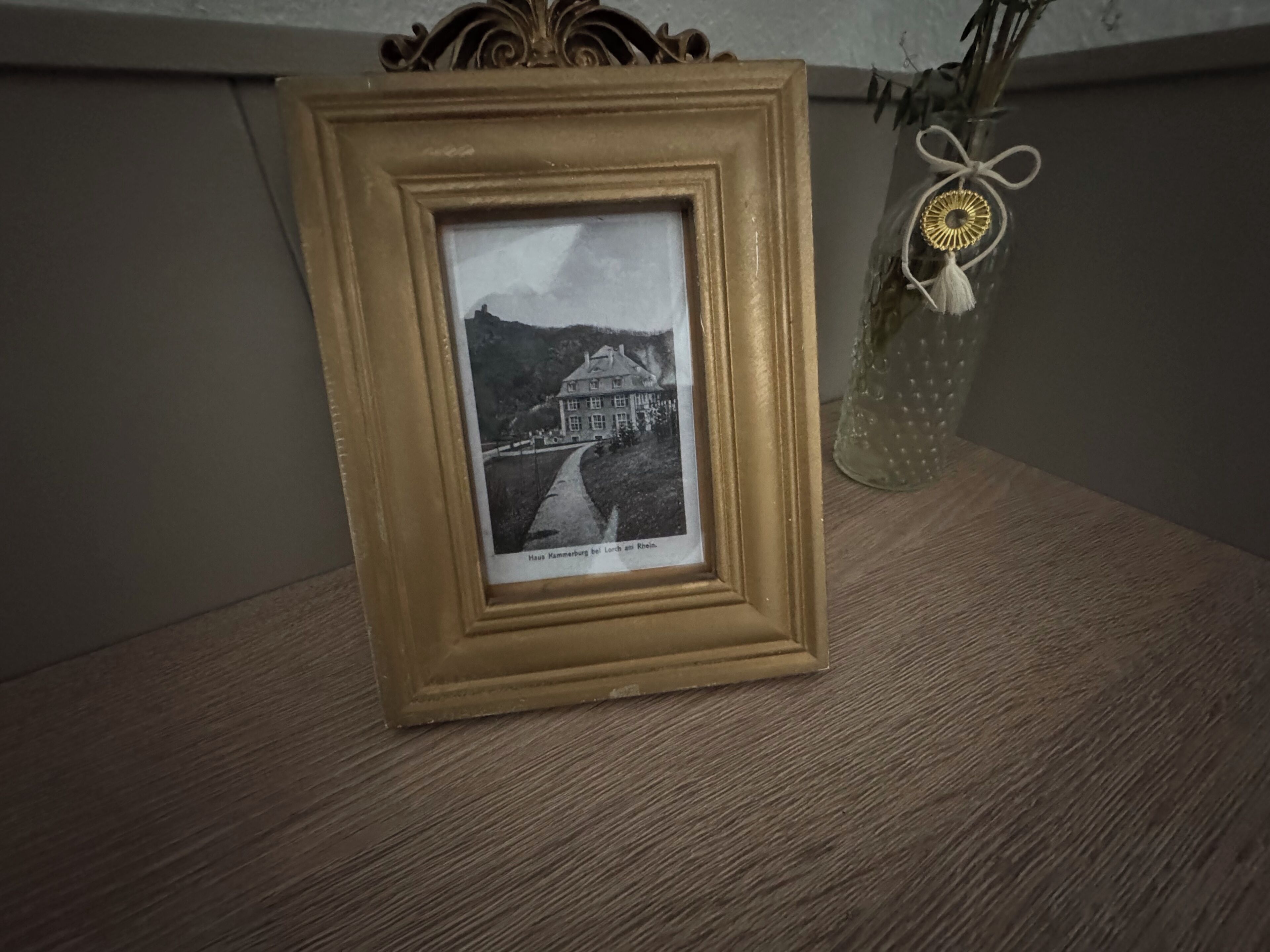 A framed black and white photograph of a building with a pathway leading to it, placed on a wooden surface.