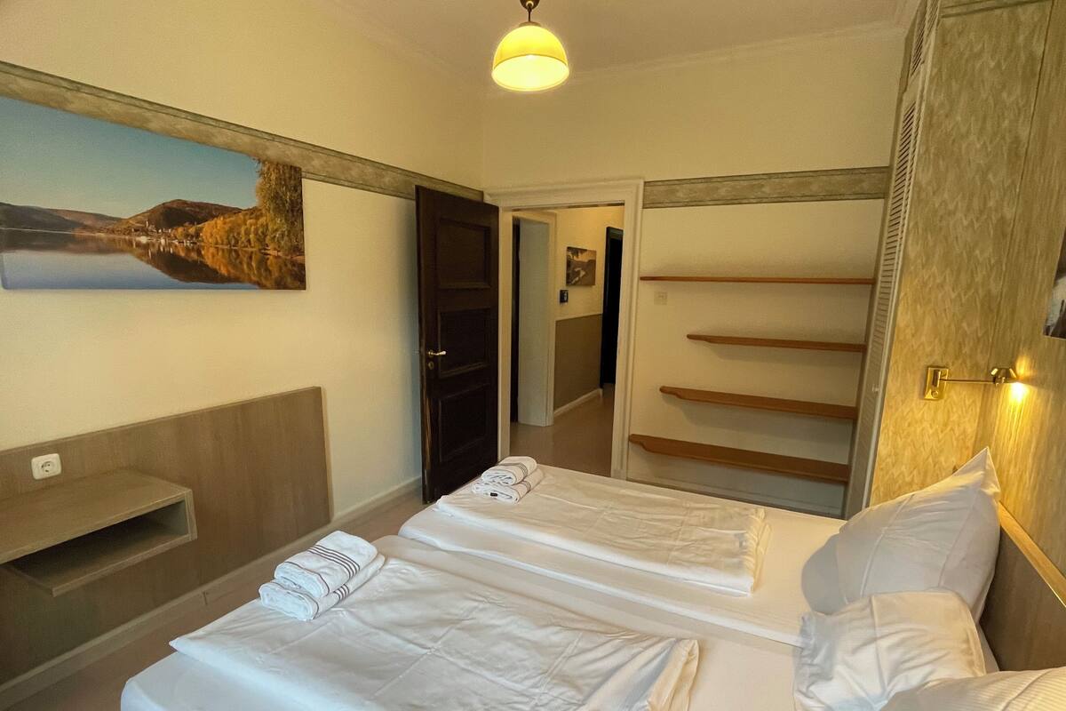 Una habitación de hotel con una cama, un cuadro, un estante de madera y un armario con espejos.