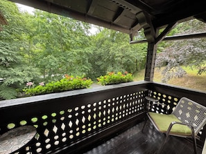 A covered outdoor seating area with a view of a garden.