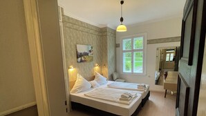 A bedroom with two beds, a window with a view, a painting on the wall, and a mirror. - Landsitz Kammerburg - Verwalterwohnhaus (Lorch)