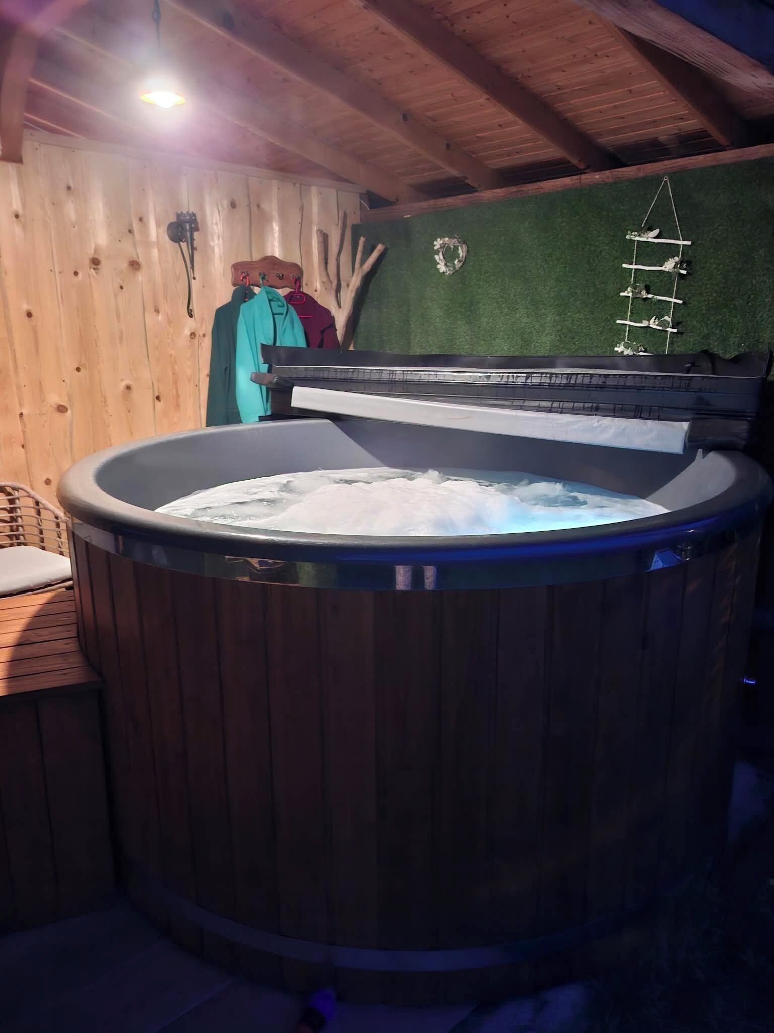 Un bain à remous dans une pièce en bois, avec un plafond en bois et une étagère fixée au mur.