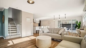 Una sala de estar moderna con un sofá, un reposapiés y una escalera.