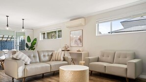 Una sala de estar moderna con un sofá color beige, una mesa de centro redonda y un ventanal grande.