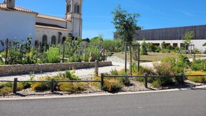 Un patio con un muro de piedra, un sendero y un edificio con una torre de reloj.