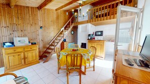 A wooden interior with a dining table, chairs, a staircase, kitchen area, and a TV. - Bois Marin - Pool & Beach 500 meters away (Bretignolles-sur-Mer)